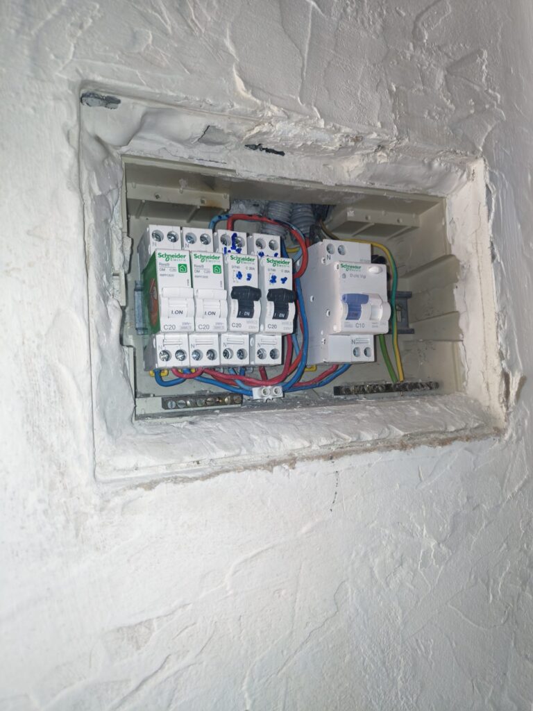 Petit coffret électrique encastré dans un mur, disjoncteurs apparents